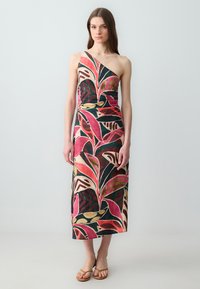 Asymmetrisches Maxikleid mit bunten Blattmustern auf dunklem Hintergrund, gefertigt aus leichtem Stoff mit tailliertem Schnitt.