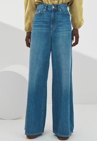 Džínové kalhoty širokého střihu vyrobené z světle modrého denimu. Vysoký pas s vybledlým vzhledem a klasickým pětipocket stylem. Rovný střih.