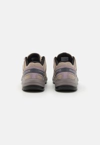 Chaussures légères d'extérieur en maille beige avec des accents gris, dotées d'une semelle flexible, d'un col rembourré et d'une semelle texturée pour une meilleure traction.