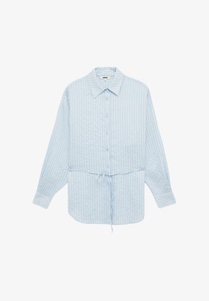Lyseblå skjorte med lange ærmer, knapper foran, tynde lodrette hvide og marineblå striber samt bindebånd foran i taljen.