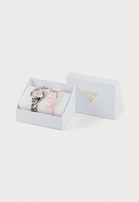 Silver and pink watch set in a white box with a geometric design. Features a metal link band and a soft pink silicone strap.