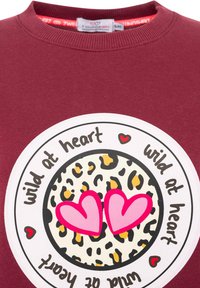 Bordowy sweatshirt z okrągłą grafiką, w której znajduje się środek w cętkowanym wzorze lamparta, różowe serca oraz napis "dziki w sercu" na czarnym tle.