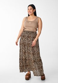Beige krūšturis ar čaulas logo, apvienots ar slāņotu leopardu raksta maksi svārku. Brūni platformas apavi ar auduma faktūru.