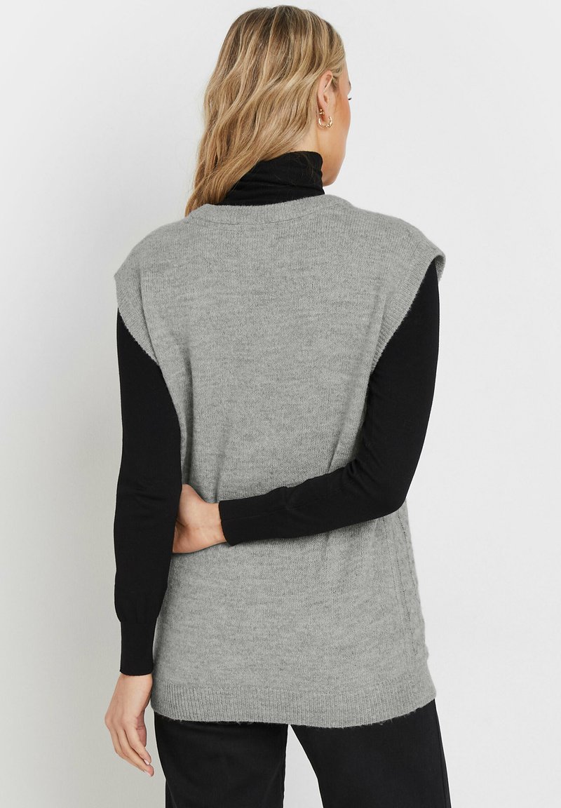 Maglione senza maniche grigio chiaro con una trama morbida, caratterizzato da un colletto rotondo e cuciture sulle spalle che cadono leggermente sopra le braccia.