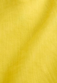 Tissu léger jaune avec une texture légèrement froissée et tissée de façon lâche.