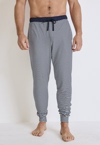 W pasiaste spodnie dresowe w kolorze granatowym i białym z bawełny, z elastycznym pasem w talii i sznurkiem do regulacji oraz zwężanymi mankietami u kostek.