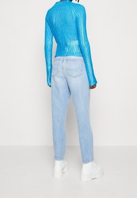 Blårandig långärmad topp med en figurnära design, tillsammans med ljusblå raka jeans och vita plattformstövlar.