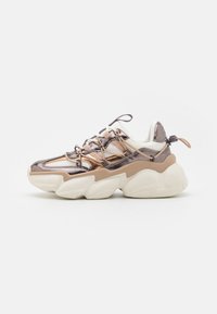 Chunky sneaker with metallic rose gold and beige overlays, white mesh, thick white sole, and beige patterned laces against a white background.