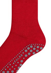 Calcetín rojo con puntos antideslizantes grises en la suela y el nombre de la marca "FALKE" integrado entre los puntos.