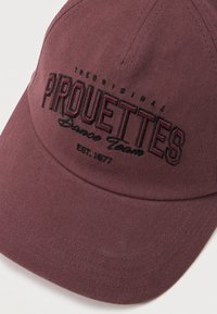 Casquette de baseball bordeaux avec texte brodé noir "Original Piruettes Dance Team EST. 1977" sur le panneau avant.