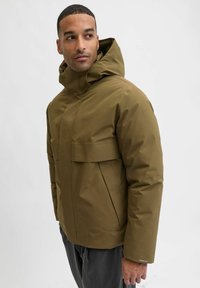 Olivgrüne wasserdichte Jacke mit hohem Kragen und verstellbarer Kapuze. Verfügt über zwei große Fronttaschen und eine glatte Nylonstruktur.