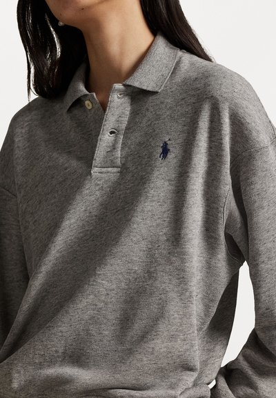 Hallide hallhallane polo-särk, millel on krae, kolm nuppu ja tumehall tikand vasakul rinnal. Pehme tekstuur, mugav lõige.