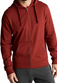 Sudadera roja con cremallera, hecha de una tela suave, que cuenta con un bolsillo frontal, capucha ajustable con cordón y puños acanalados con una textura suave.