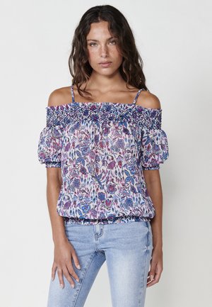 Top floreale scollato con stampa blu, rosa e bianca. Caratterizzato da un collo smock e maniche corte a sbuffo. Tessuto morbido e leggero.