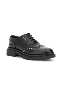 Zwarte leren brogue schoen met spitse neus, decoratieve perforaties, zilveren studs langs de naden en robuuste rubberen zool.