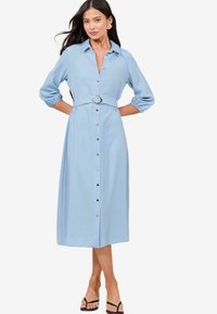 Vestito camicia azzurro chiaro con colletto, maniche a tre quarti e vita con cintura dotata di fibbia circolare. Chiusura frontale con bottoni e lunghezza a metà polpaccio.