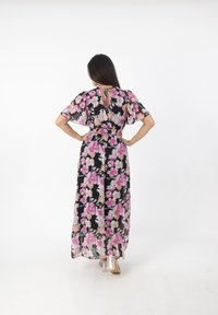 Robe maxi en tissu noir léger avec un imprimé floral vibrant rose et crème. Manches courtes à volants, taille élastique et détail de dos en forme de trou de clé.