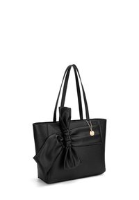 Zwart lederen tote bag met een gestructureerde afwerking, voorzien van een grote strikaccent aan de zijkant en verstelbare hengsels. Gouden charme eraan bevestigd.