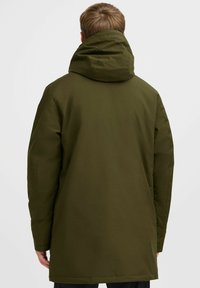 Maslinasto zeleni parka s velikom kapuljačom, dugim rukavima i ravnim krojem, s glatkom teksturom i minimalnim detaljima šivanja.