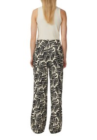 Zwart-witte broek met bladraster, met een loose fit, hoge taille en twee zijzakken, gedragen met een mouwloos ribgebreid topje.