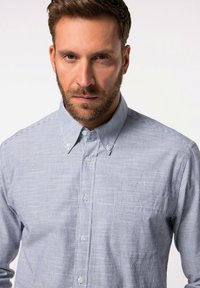 Camicia button-up di colore azzurro chiaro con righe bianche, dotata di colletto, tasca frontale e chiusura con bottoni. Realizzata in un tessuto dalla texture liscia.