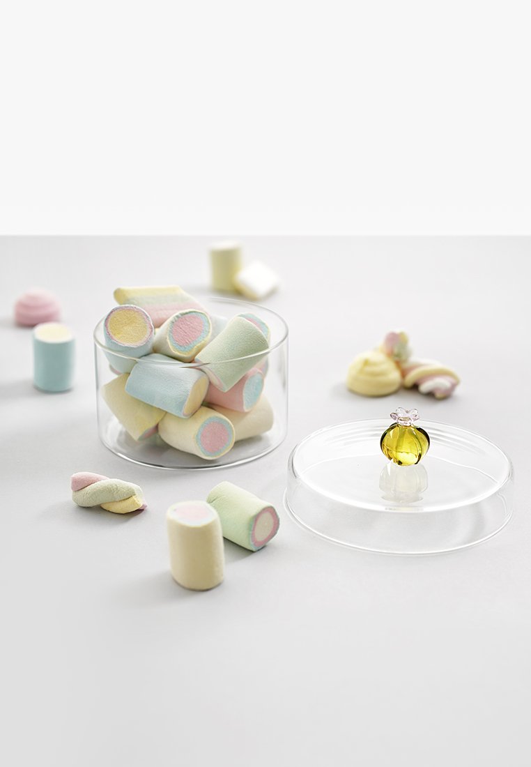 Kolorowe cukierki z pianki w szklanym słoiku, z pastelowymi kształtami i wzorami. Mała szklana ozdoba przed słoikiem z kwiatowym akcentem.