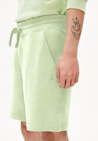 Lichtgroene katoenmix shorts met een verstelbare tailleband, zijzakken en een subtiele reliëflogo op het linkeronderbeen. Gladde textuur.