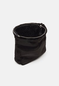 Zwarte bonttas met een zachte textuur en een ritssluiting, voorzien van een zwart patroon aan de binnenvoering. Cilindervormig met een brede opening.