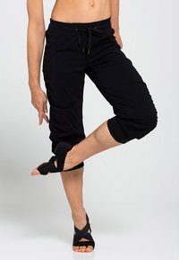 Černé kapri kalhoty z lehké látky s pasem na stažení, zkrácenou délkou a postranními kapsami. Texturované detaily na lemech.