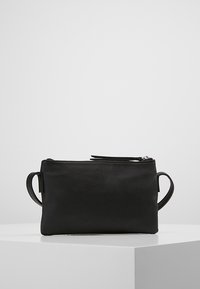 Musta nahkainen pussi, jossa on sileä pinta, vetoketjusuljenta ja kaksi sivukahvaa. Suorakulmainen muoto, minimalistinen muotoilu, sopii pienille esineille.