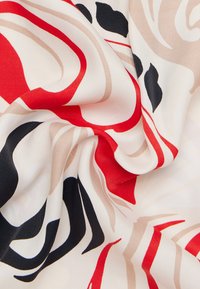 Tessuto multicolore con motivi vorticosi in rosso, nero, beige e crema, che mostra una texture liscia e una caduta leggera.