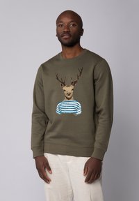 Grüne Sweatshirt mit einem Hirsch mit Geweih, der ein blau-weiß gestreiftes Shirt trägt, vor einem hellgrauen Hintergrund präsentiert.