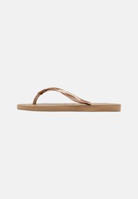 Chinelo castanho com uma correia texturizada e sola plana. A correia apresenta um detalhe met�álico, colocado sobre uma palmilha bege.