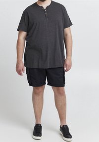 Maglia henley grigia a maniche corte con tre bottoni, abbinata a pantaloni cargo neri e sneackers nere. Look casual e vestibilità rilassata.