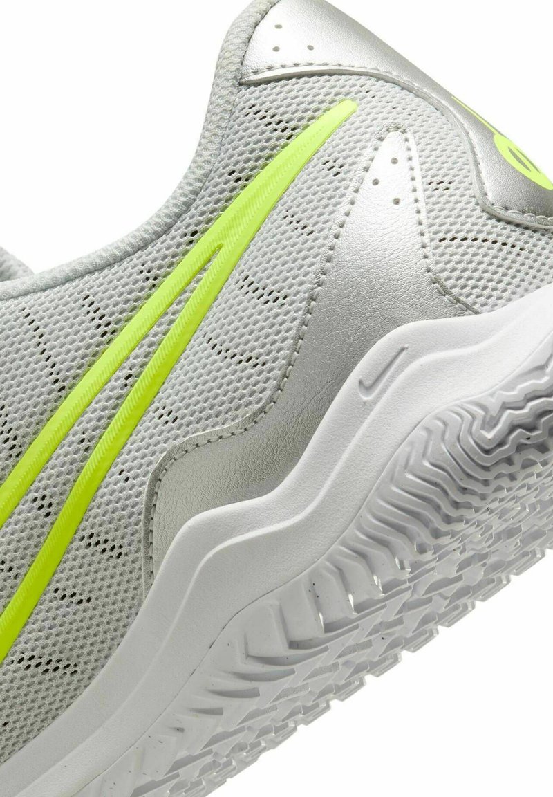 Jasnoszary but sportowy z siateczkową cholewką, neonowożółtymi akcentami, teksturowaną powierzchnią oraz białą gumową podeszwą z zygzakowatym bieżnikiem.