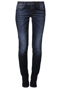 Jeans de mezclilla azul oscuro con un corte ajustado, diseño de cinco bolsillos, ligero desgaste y sutiles detalles de costura a lo largo de las costuras.