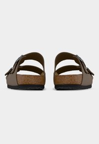 Ζευγάρι καφέ σανδάλια με δύο ρυθμιζόμενα λουριά και εσωτερική σόλα από φελλό, απεικονιζόμενα από πίσω σε απλό λευκό φόντο.