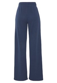Wijde broekspijpen in marineblauwe ribgebreide stof met een elastische tailleband. De broek heeft een zachte textuur en verticale strepen voor extra detail.