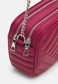 Borsa a mano in pelle fucsia con motivo trapuntato, due zip argento e tracolla in catena argentata. Caratterizzata da una forma rettangolare e una texture liscia.