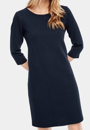 Robe bleu marine avec des manches 3/4, encolure ronde, fabriquée en tissu texturé. Design longueur genou, détails minimalistes, coupe décontractée.