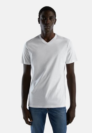 Witte korte mouwen V-hals T-shirt van katoen. Glad textuur met een ontspannen pasvorm. Gepaarde met blauwe jeans; eenvoudig ontwerp zonder graphics.