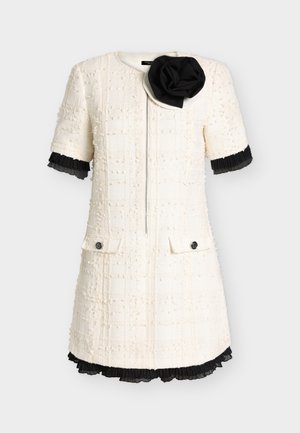 Rövid ujjú krémszínű texturált ruha elülső cipzárral, fekete pliszírozott szegéllyel az ujjakon és az alján, fekete szövet virág részlettel a galléron.