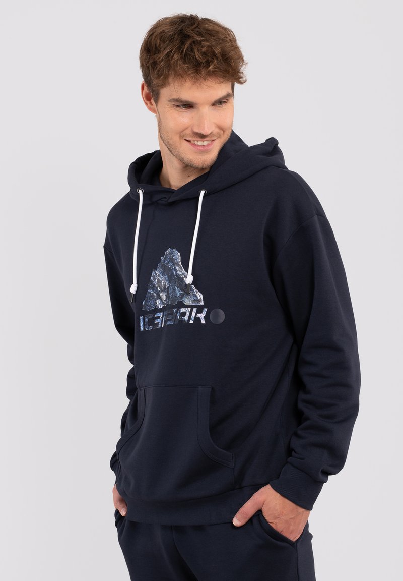 Marineblaue Kapuzenjacke mit einer Fronttasche, weißen Kordeln und einem grafischen Design, das einen Berg und den Text "ICEPEAK" mit silbernen Akzenten zeigt.