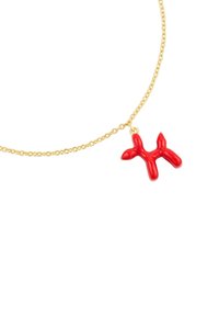 Raudona balioninė šuo pakabukas ant auksinės grandinės. Pakabukas turi blizgantį, lygų paviršių ir yra apvalių formų su žaismingu dizainu.