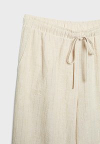 Béžové ľanové nohavice so zvislými striebornými pruhmi, s elastickým pásom a predným šnúrkovaním.