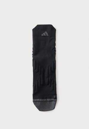 Chaussette de sport noire avec motif texturé, bout gris, petit logo Adidas près du haut et indicateur de pied droit, sur fond blanc.