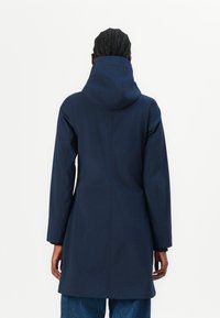 Manteau waterproof marine avec capuche, présentant une coupe droite et des manches longues. Texture lisse et design minimal sans matériel visible.