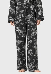 Czarne spodnie piżamowe z białym wzorem kwiatów i gwiazdek, z elastycznym paskiem, szerokimi nogawkami i kontrastowym wykończeniem. Miękki materiał tekstylny.