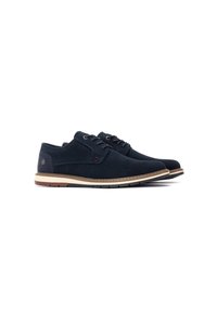 Zapatos de ante azul marino oscuro con punta redonda, diseño de cordones, suela beige en contraste y un pequeño logotipo circular en el talón.