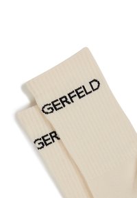 Kermansatekkisukat mustalla "GERFELD" -logolla. Pehmeä tekstiili, keskipitkä pituus, joka on varustettu sileällä pinnalla ja rakenteellisella suunnittelulla.